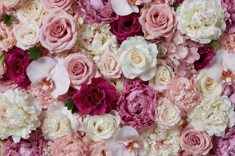 Dense floral wall arrangement of pink white and magenta roses peonies and orchids