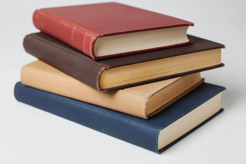 Four hardcover books stacked unevenly on a plain white surface