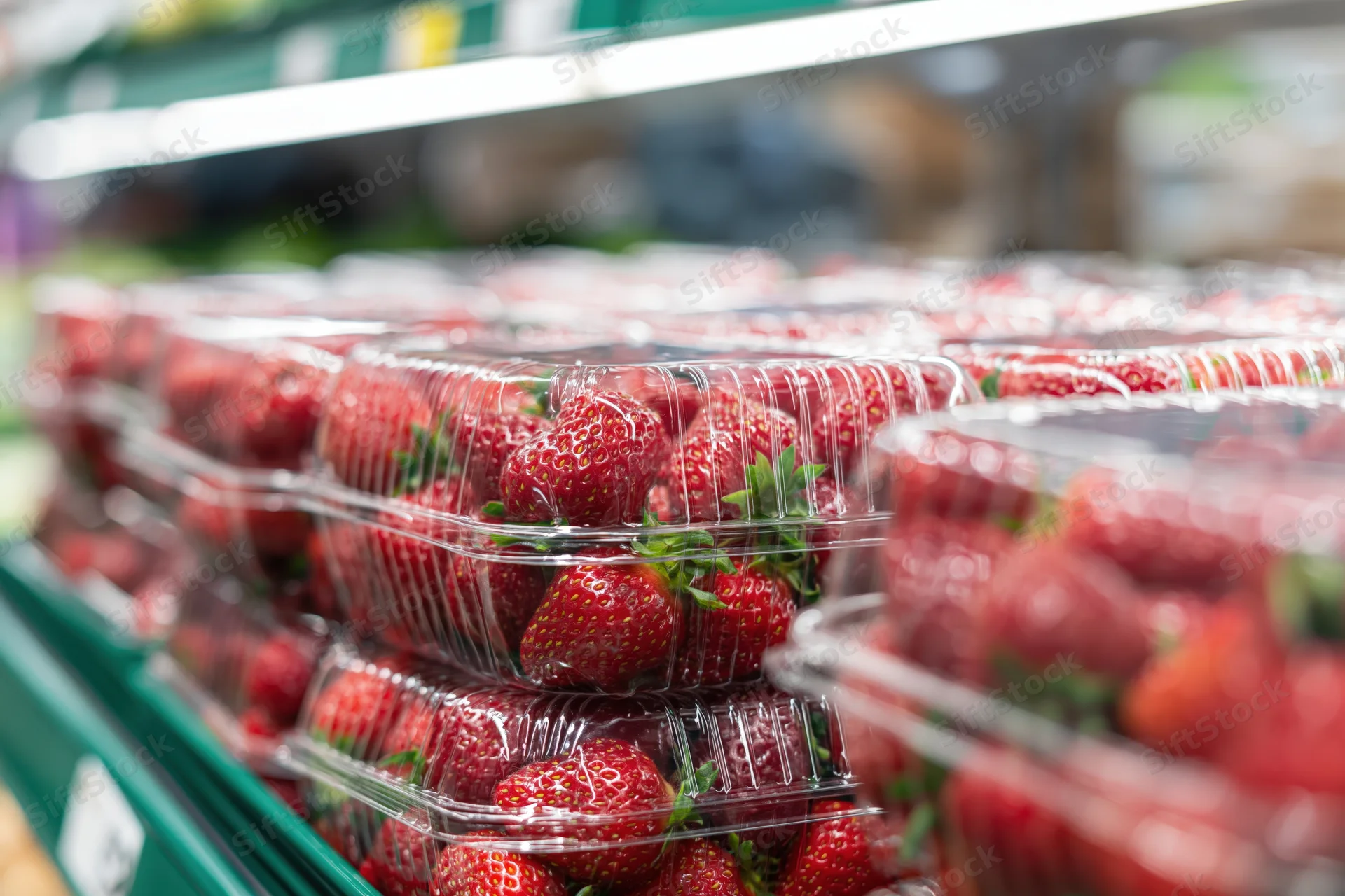 Fresh strawberries in clear plastic clamshell containers on a supermarket shelf