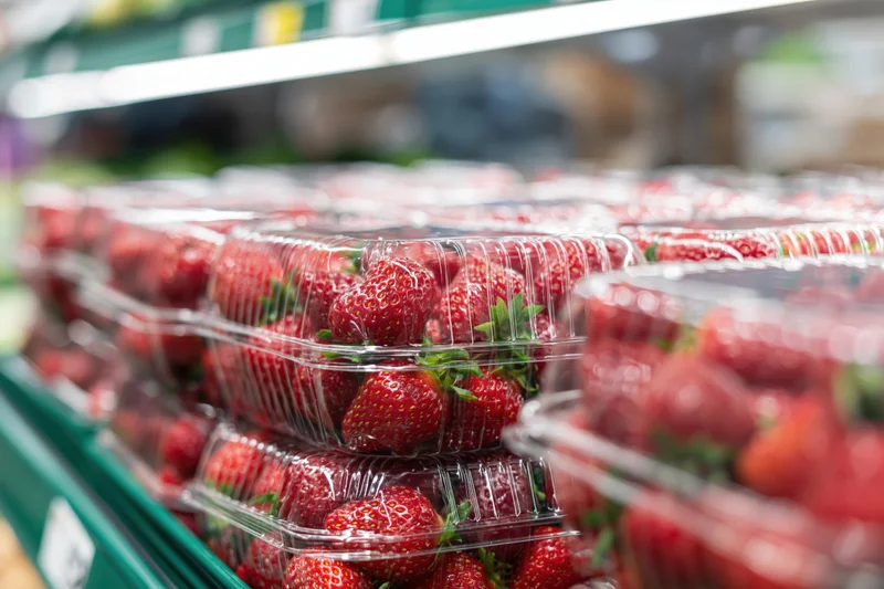 Fresh strawberries in clear plastic clamshell containers on a supermarket shelf