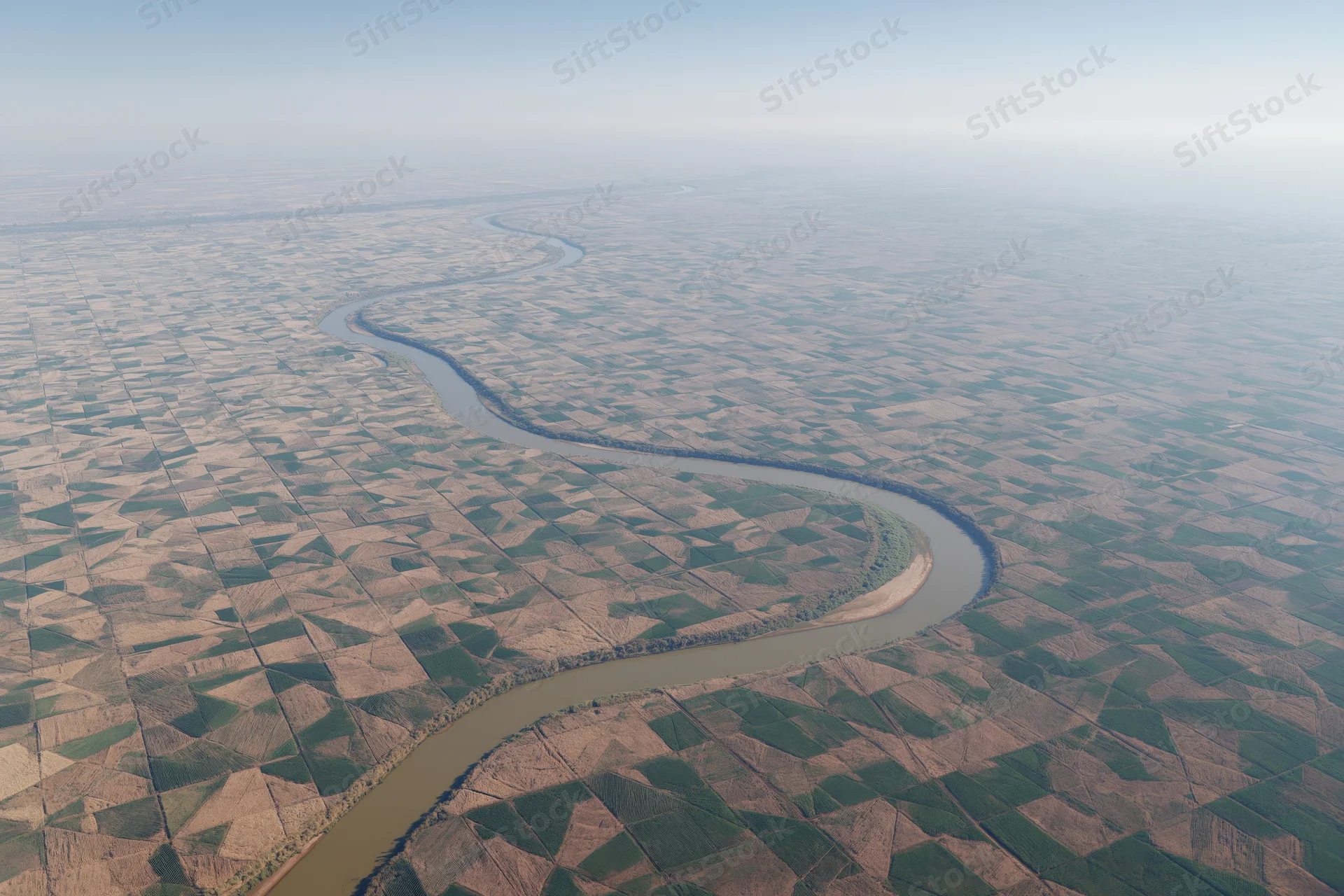 Aerial view of a meandering river cutting through patchwork farmland