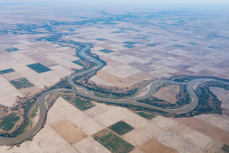 Aerial view of a meandering river cutting through farmland fields