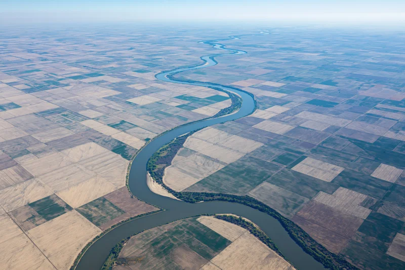Aerial view of a meandering river cutting through patchwork farmland