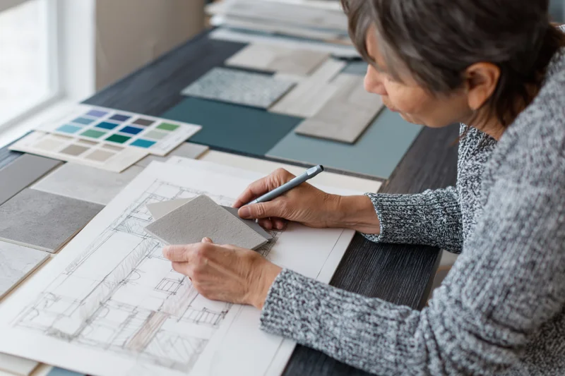 Interior designer reviewing blueprint with material samples on desk