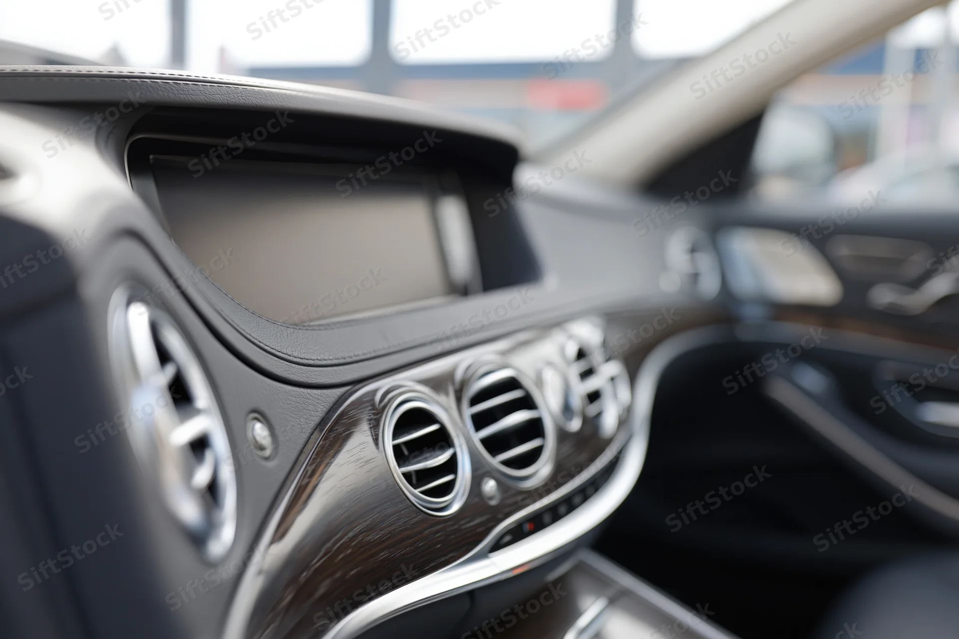 Luxury sedan dashboard with wood trim and chrome vents viewed from center console angle