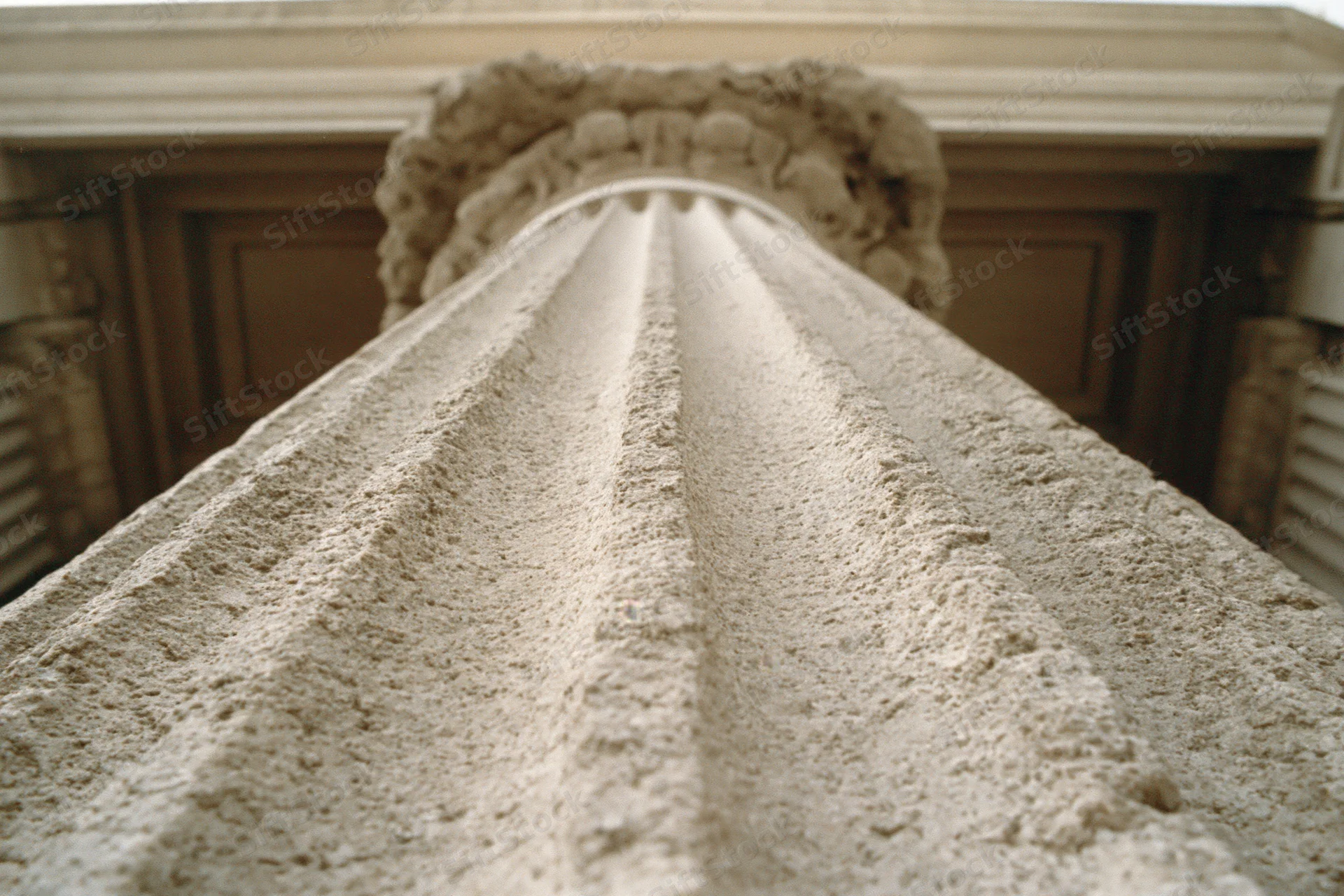 Low-angle view of fluted stone column shaft leading up to ornate capital and entablature
