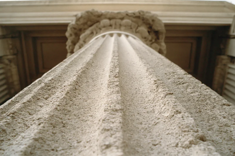 Low-angle view of fluted stone column shaft leading up to ornate capital and entablature