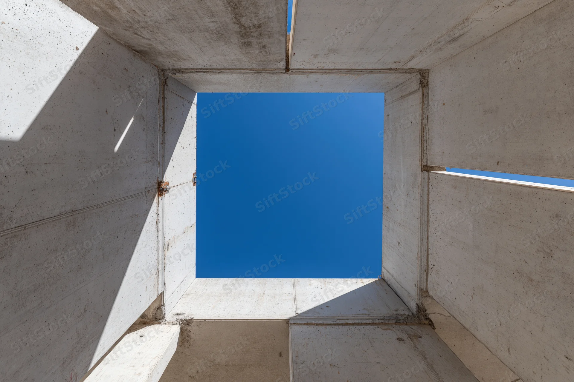 View through unfinished concrete walls toward blue sky