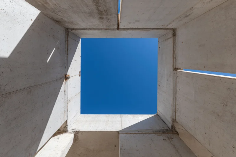 View through unfinished concrete walls toward blue sky