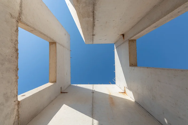 Upward view through unfinished concrete walls of a building under construction