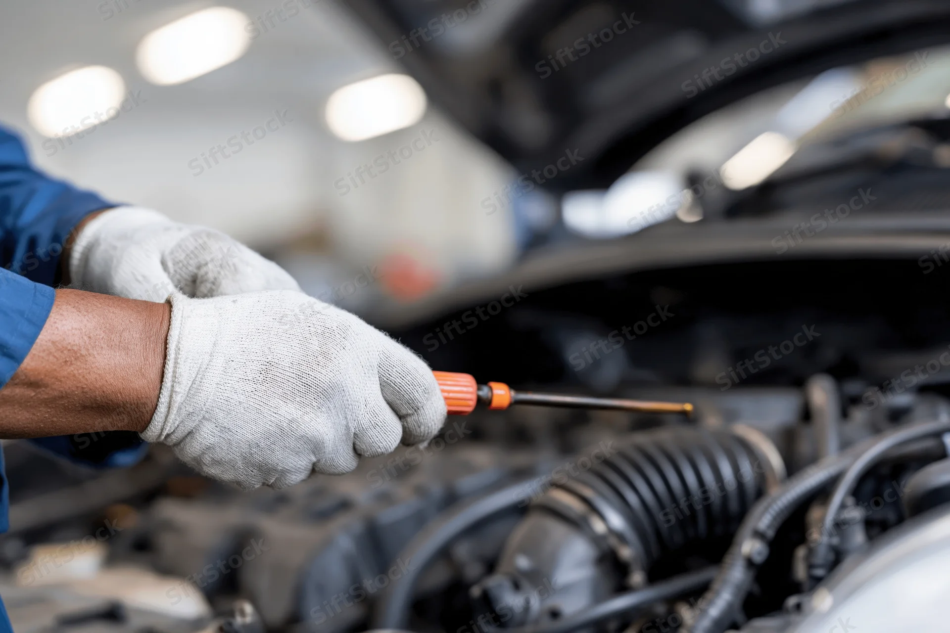 Mechanic checking oil level with dipstick in car engine bay