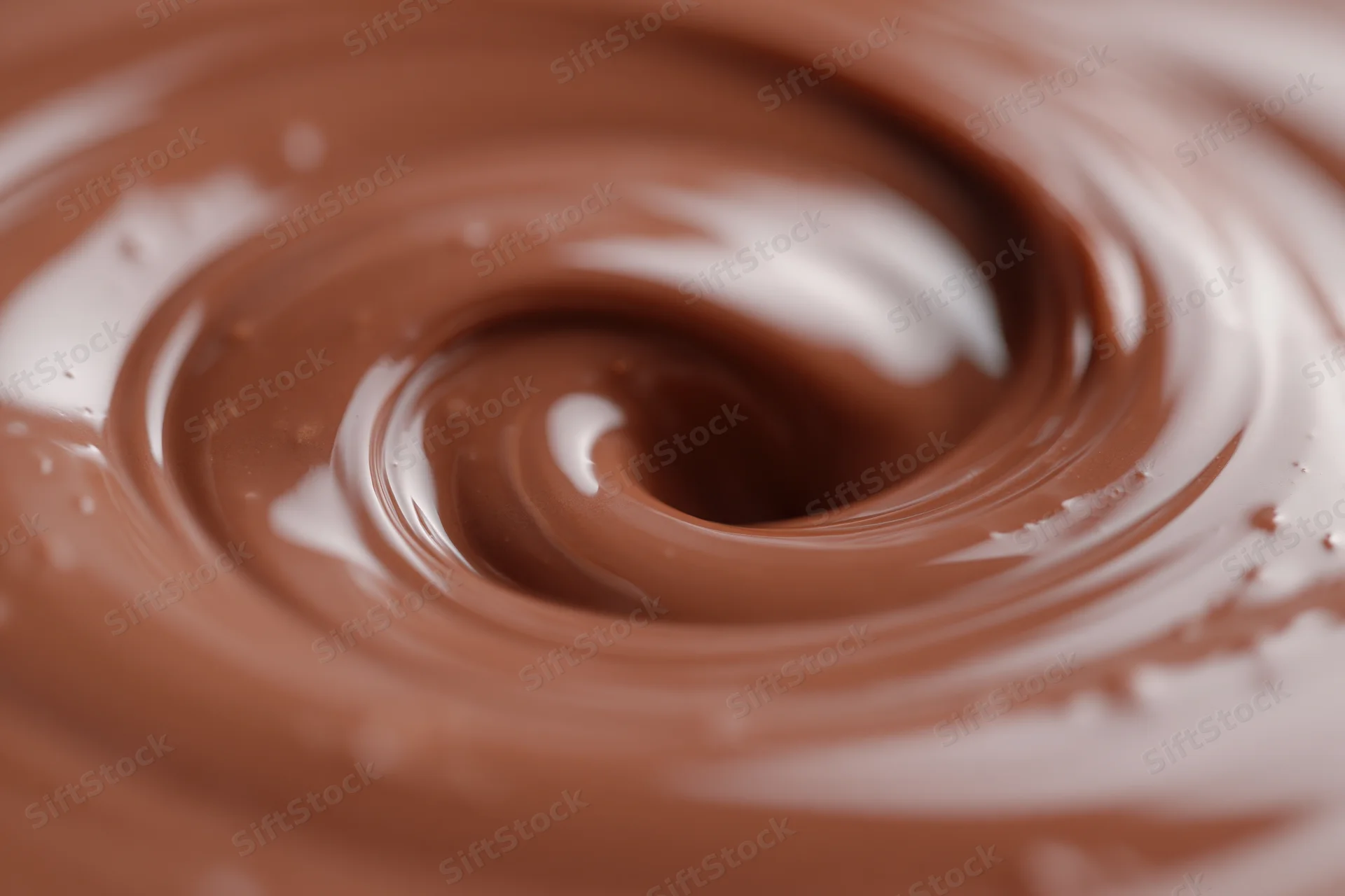 Melted milk chocolate swirling in a slow vortex filling the frame