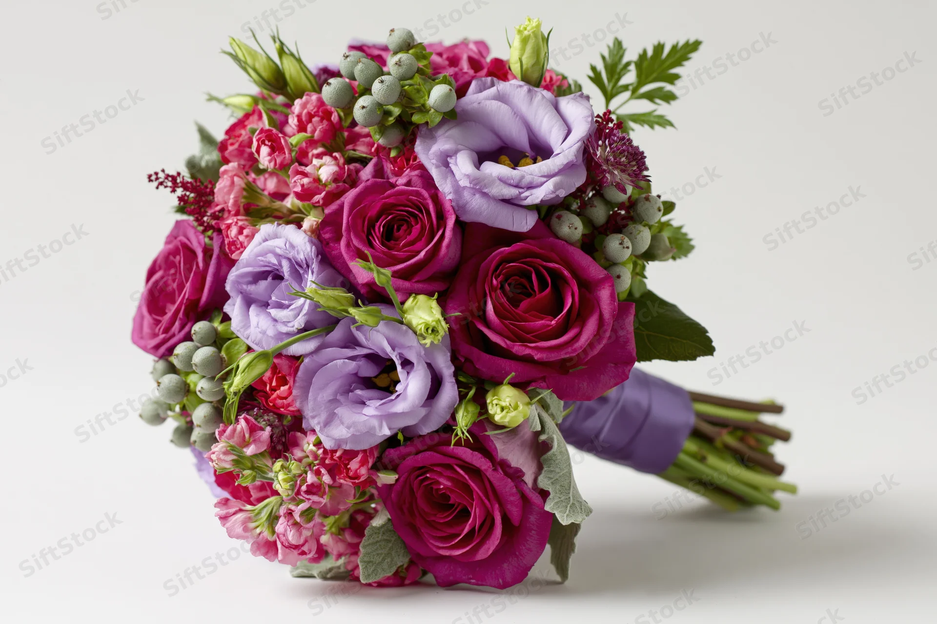 A mixed flower bouquet with deep magenta roses and lilac lisianthus arranged with greenery and berries on a white background