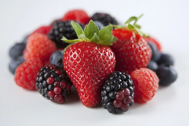 Mixed fresh berries piled on a white surface
