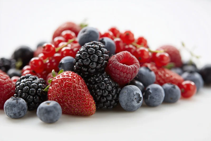 Mixed fresh berries piled together on a white surface
