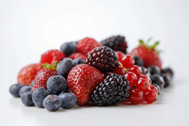 Mixed fresh berries piled together on a white surface