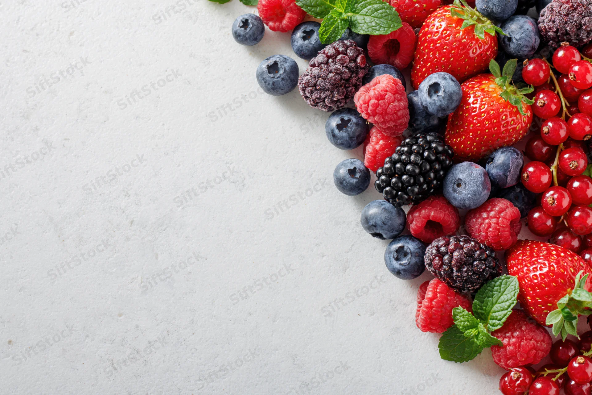 Mixed fresh berries arranged along the right edge of a white surface