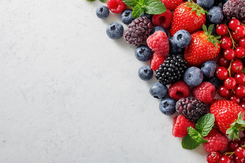 Mixed fresh berries arranged along the right edge of a white surface