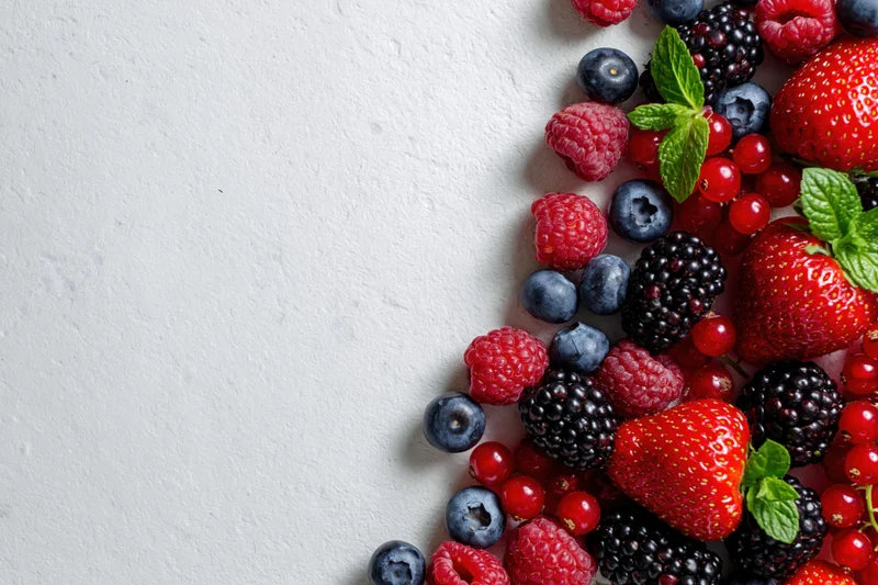 Mixed fresh berries arranged along the right edge of a white surface