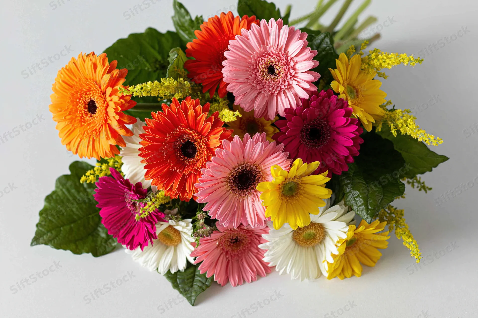Mixed gerbera daisy bouquet arranged loosely on white surface