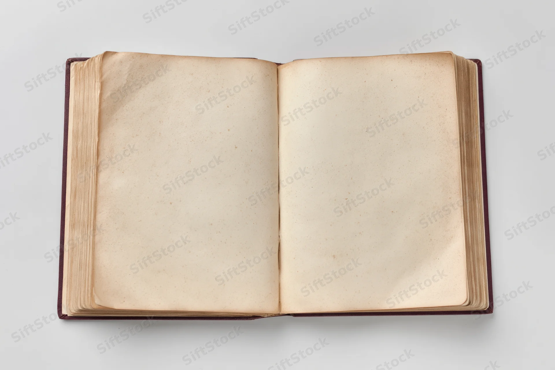 Open hardcover book with blank aged pages on white surface
