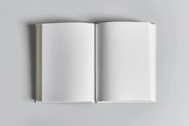 Open blank white paperback book lying flat on a gray surface