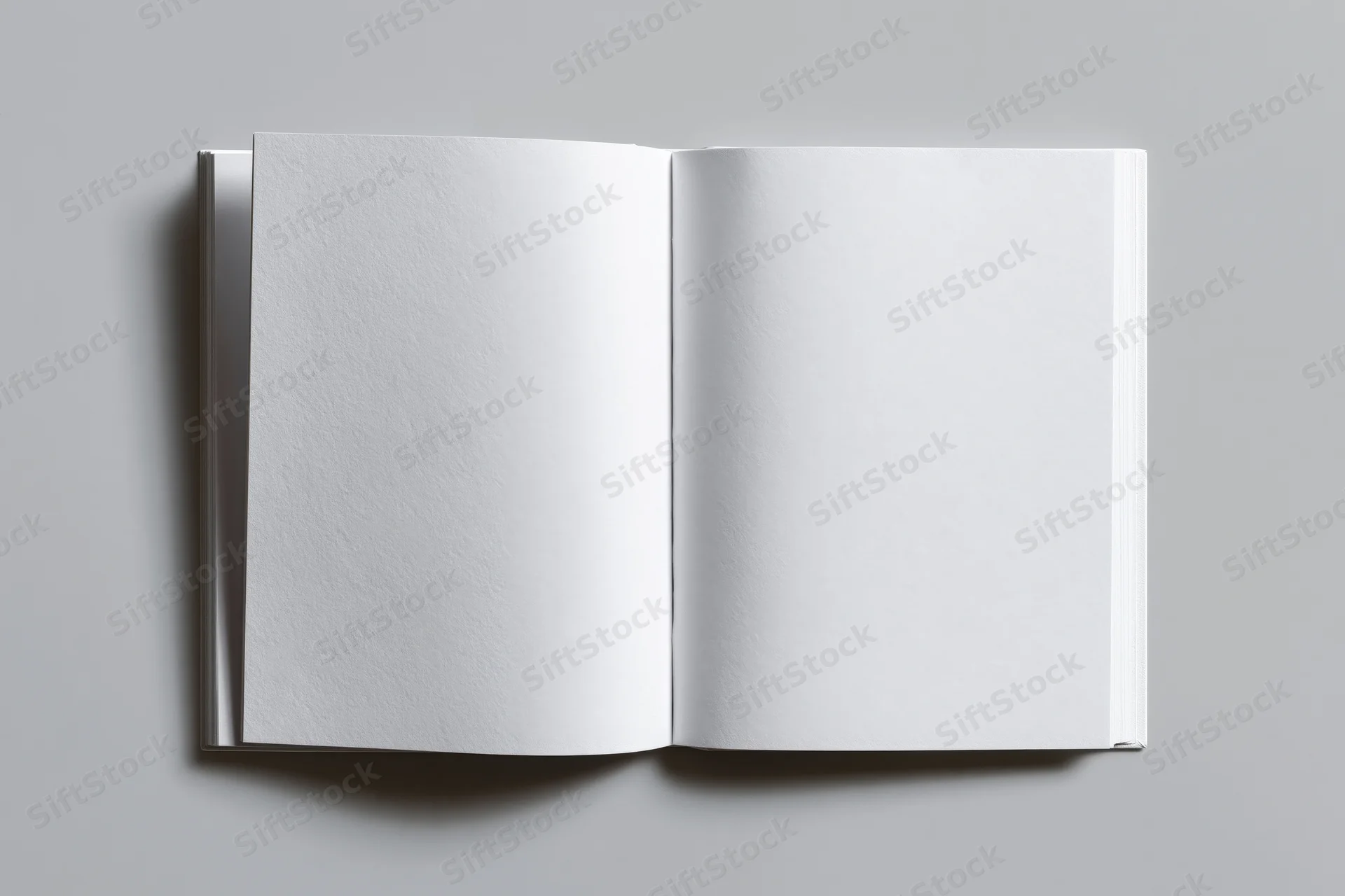Open blank white paperback book lying flat on gray surface