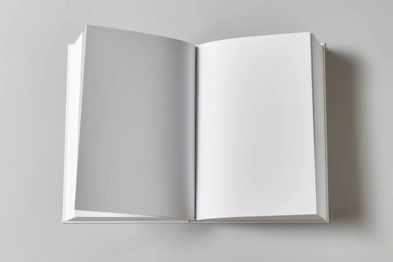 Open blank white paperback book lying flat on a gray surface