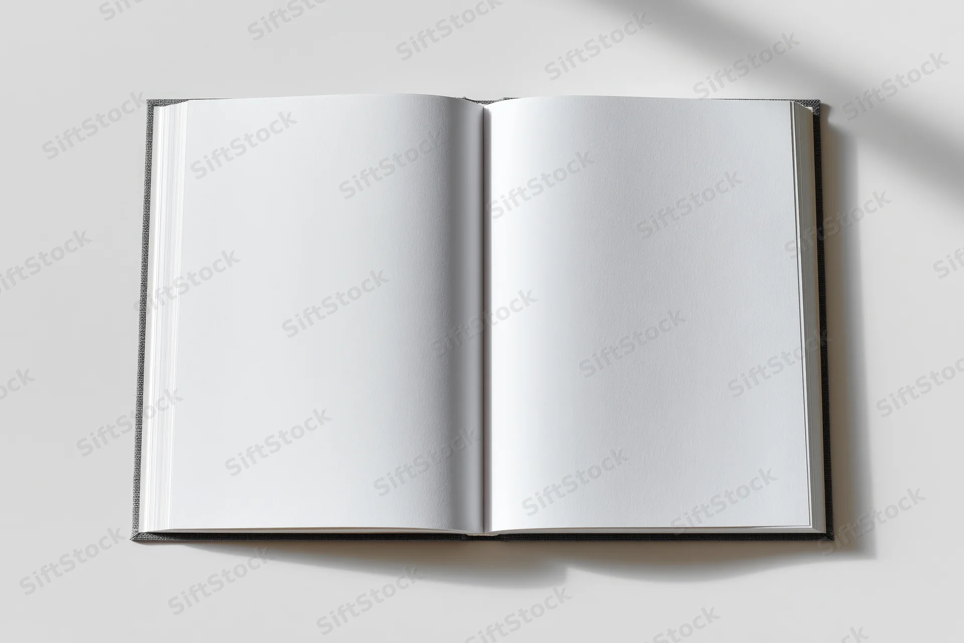 Open hardcover book with blank white pages lying flat on a white surface