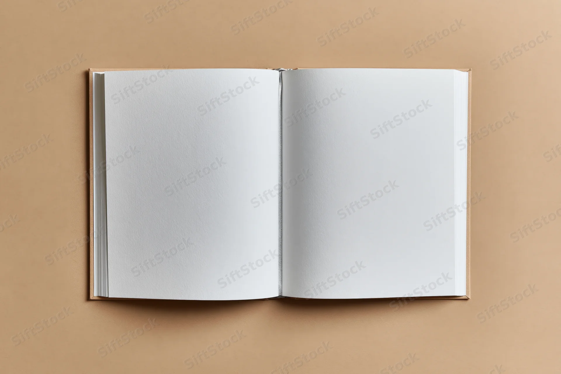 Open hardcover book with blank white pages lying flat on beige surface