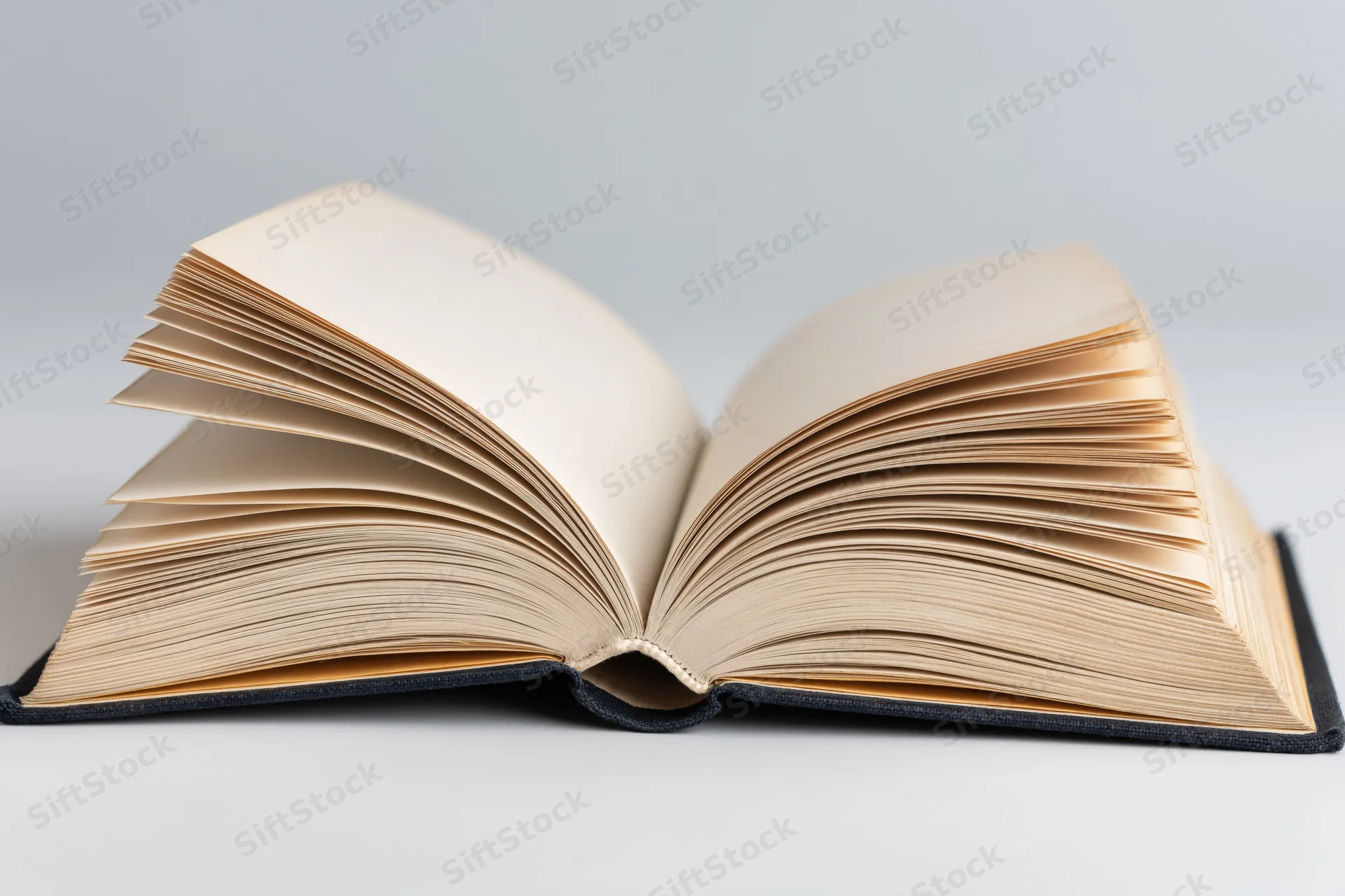 Open hardcover book lying flat with pages spread wide on a plain surface
