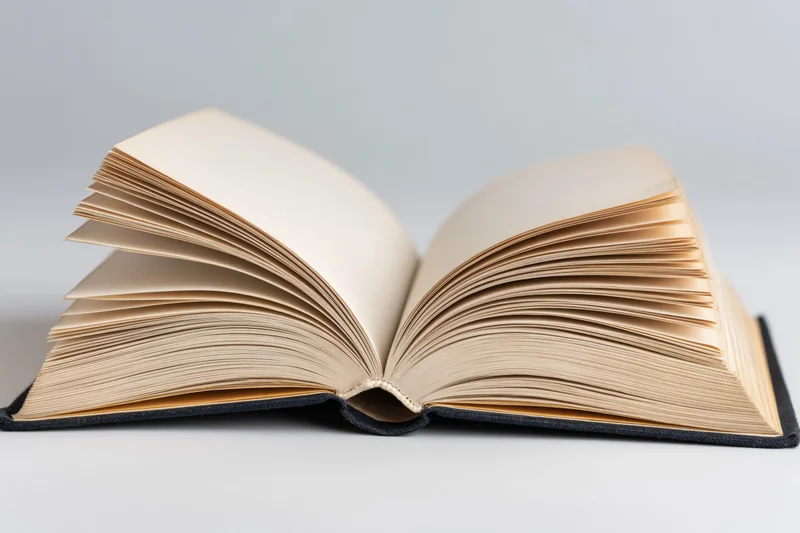 Open hardcover book lying flat with pages spread wide on a plain surface