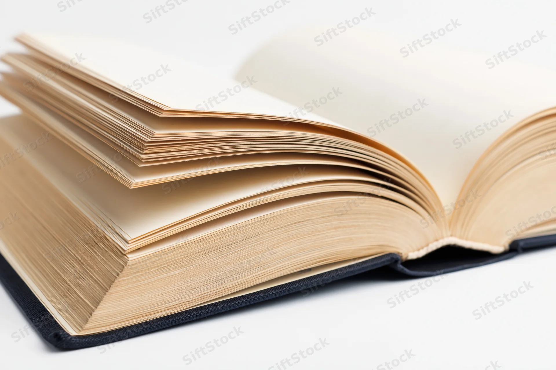 Open hardcover book lying flat with pages spread wide on white surface