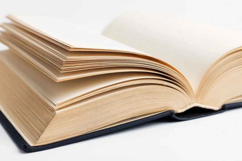 Open hardcover book lying flat with pages spread wide on white surface