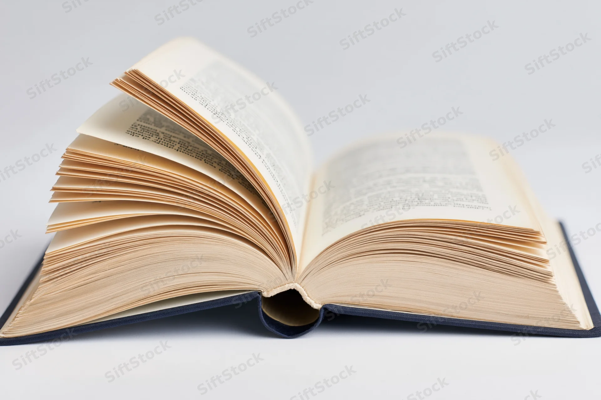 Open hardcover book lying flat with pages spread wide on white surface