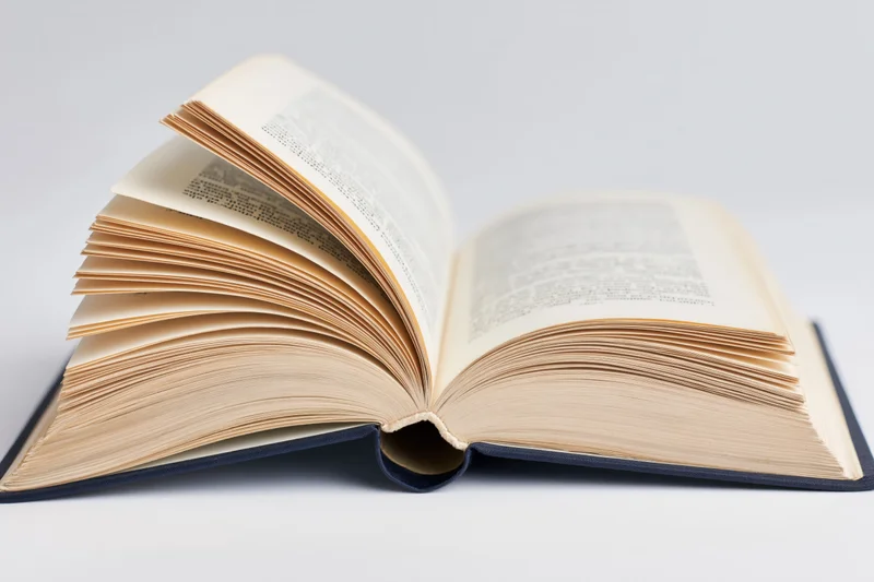 Open hardcover book lying flat with pages spread wide on white surface
