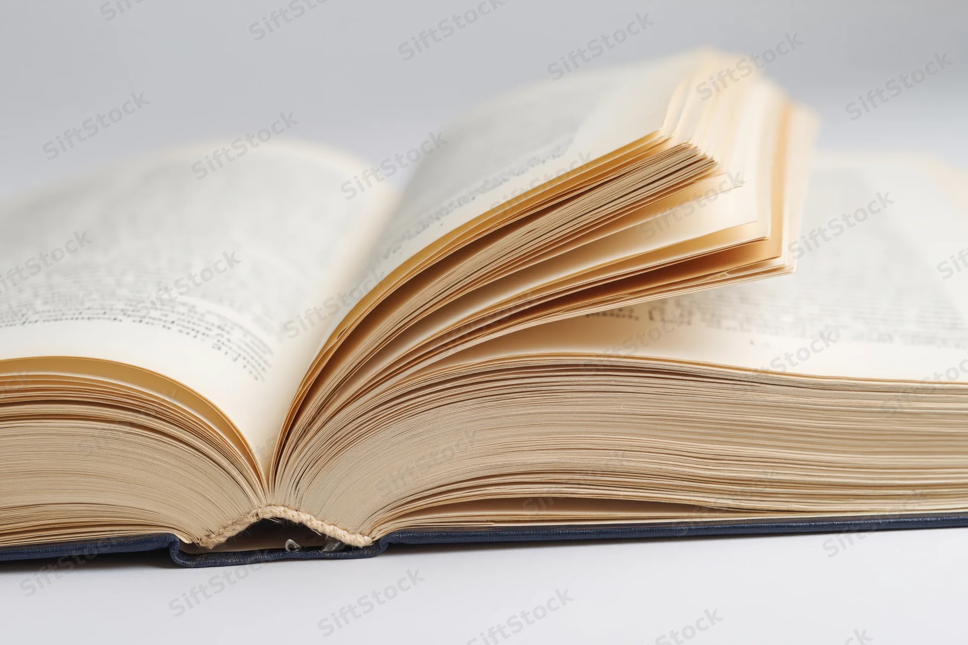 Open hardcover book lying flat with pages spread wide on white surface