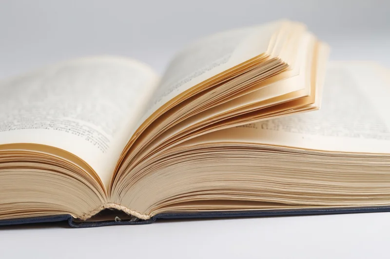 Open hardcover book lying flat with pages spread wide on white surface