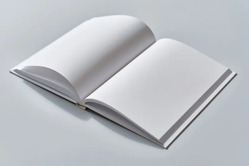 Open hardcover book with blank white pages lying flat on a gray surface