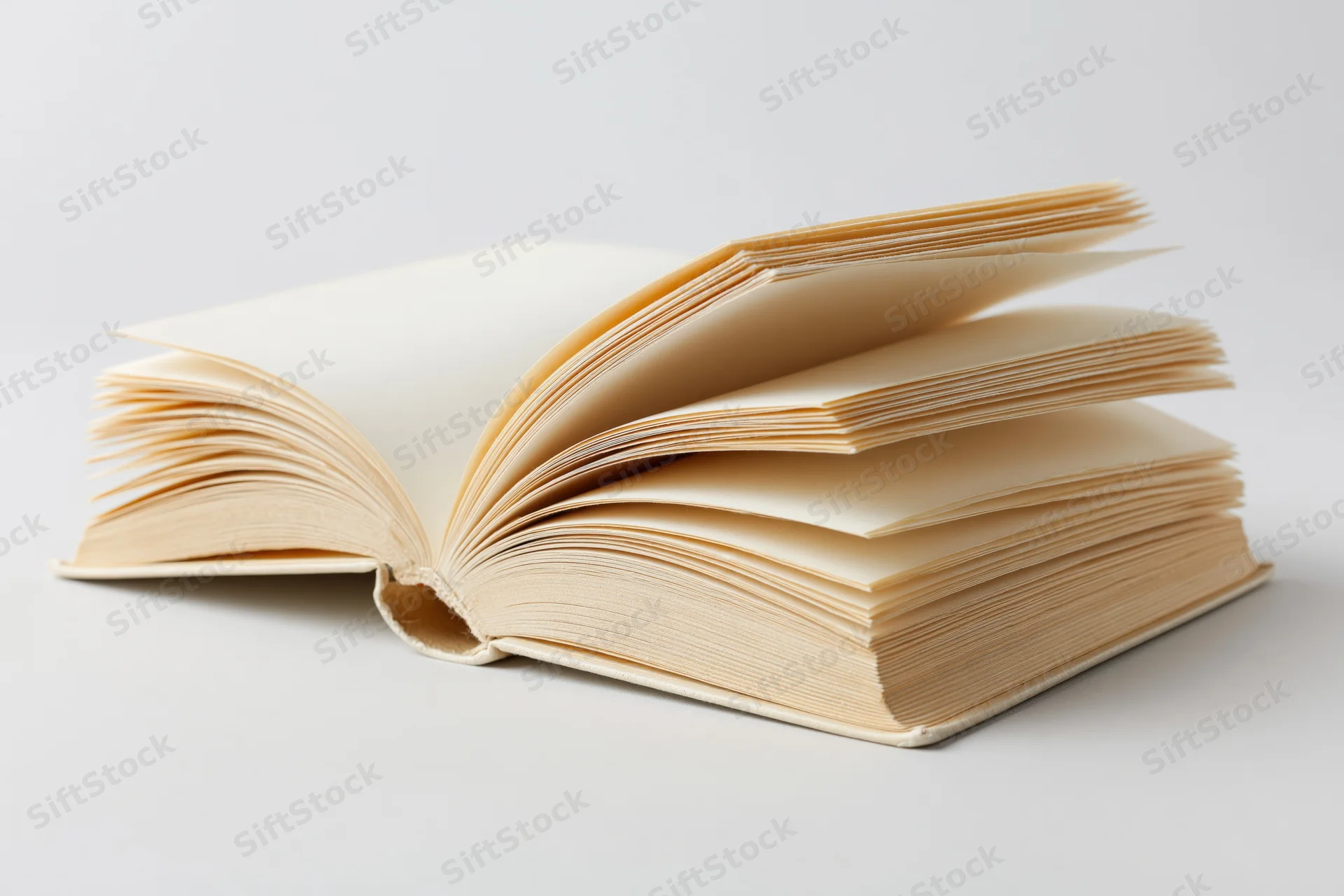 Open hardcover book with pages fanned out on a white surface