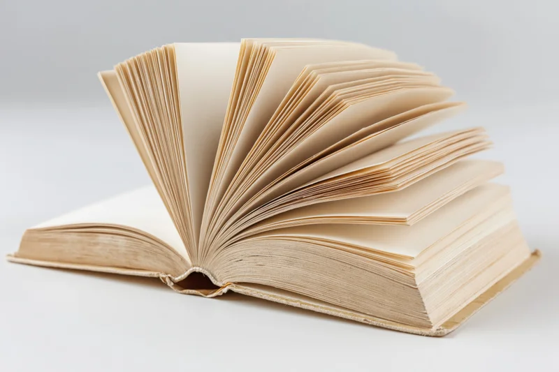 Open hardcover book with pages fanned out on white background
