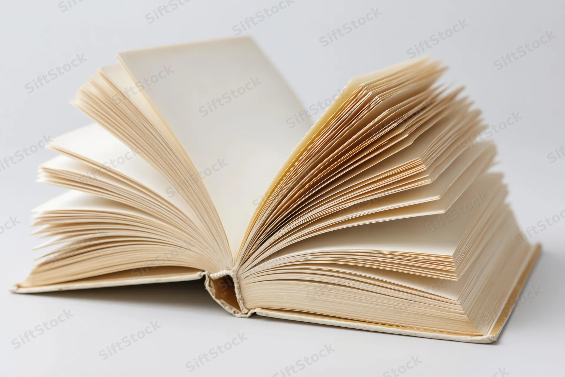 Open hardcover book with pages fanned out on white background