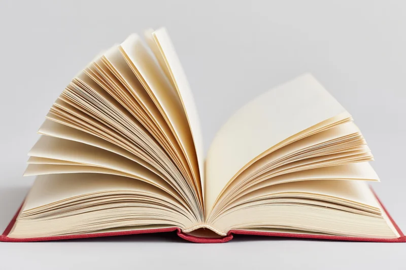 Open hardcover book with pages fanned wide and spine resting flat on white surface