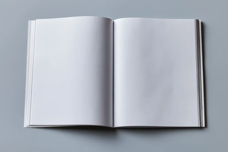 Open softcover book with blank white pages lying flat on gray surface