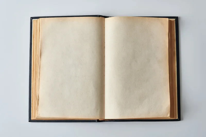Open vintage hardcover book with blank aged pages on white surface