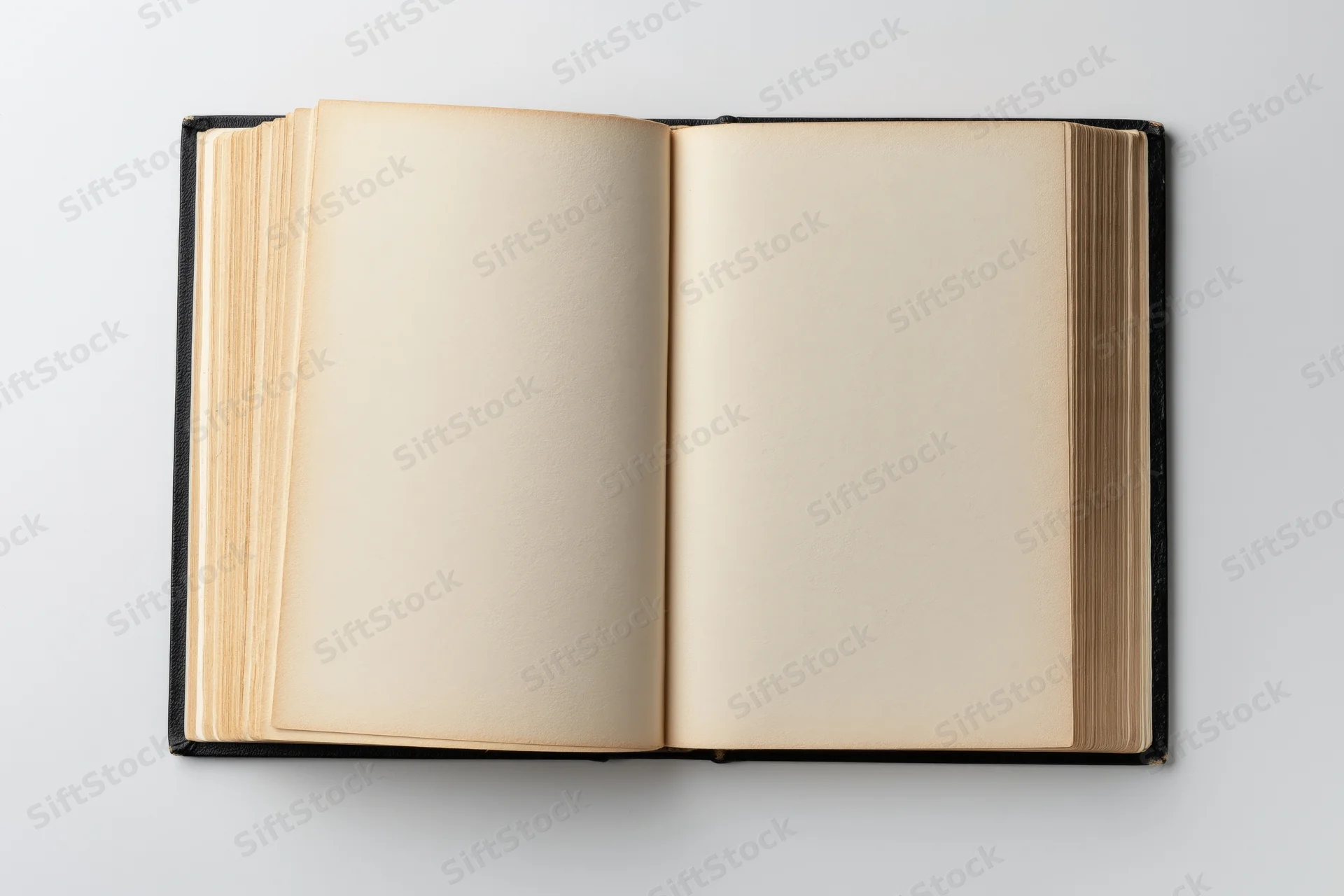 Open hardcover book with blank beige pages lying flat on white surface
