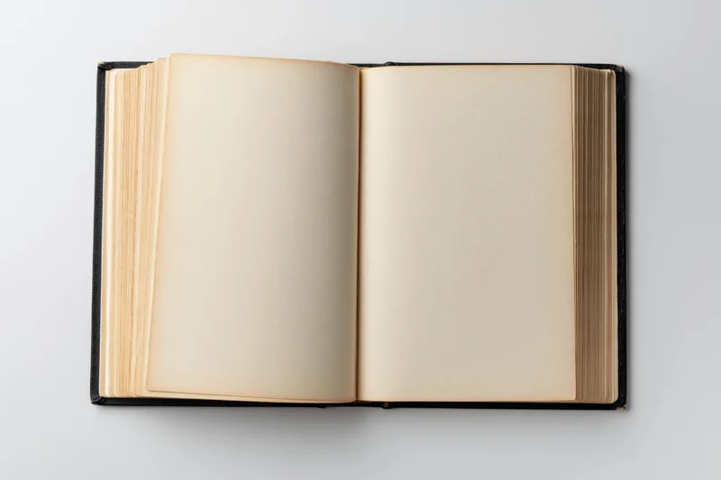 Open hardcover book with blank beige pages lying flat on white surface