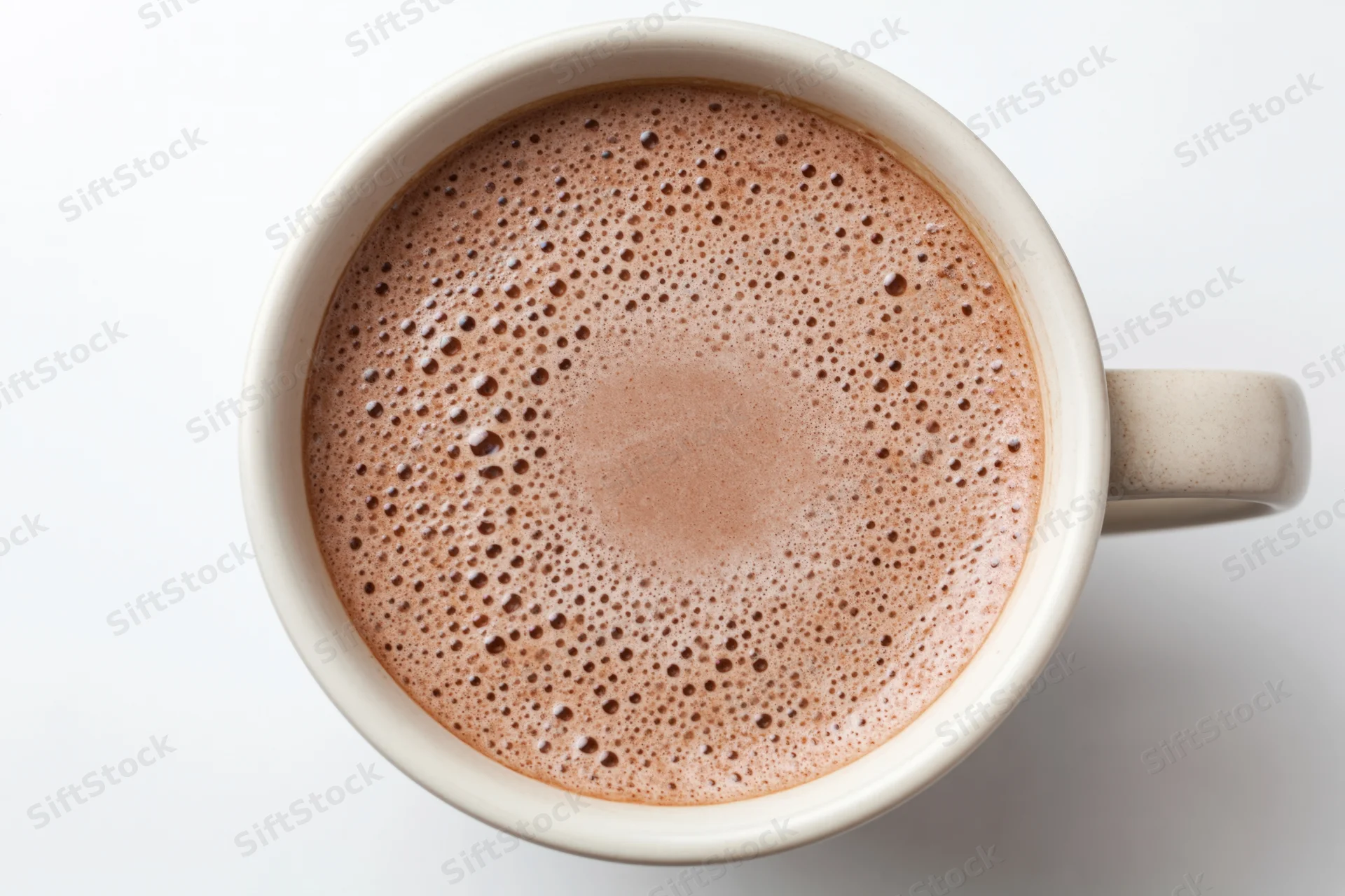 Overhead view of a white ceramic mug filled with frothy hot cocoa on a plain white surface