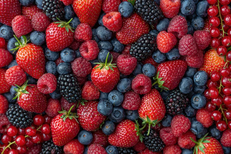 Overhead flat lay of mixed fresh berries densely covering the surface
