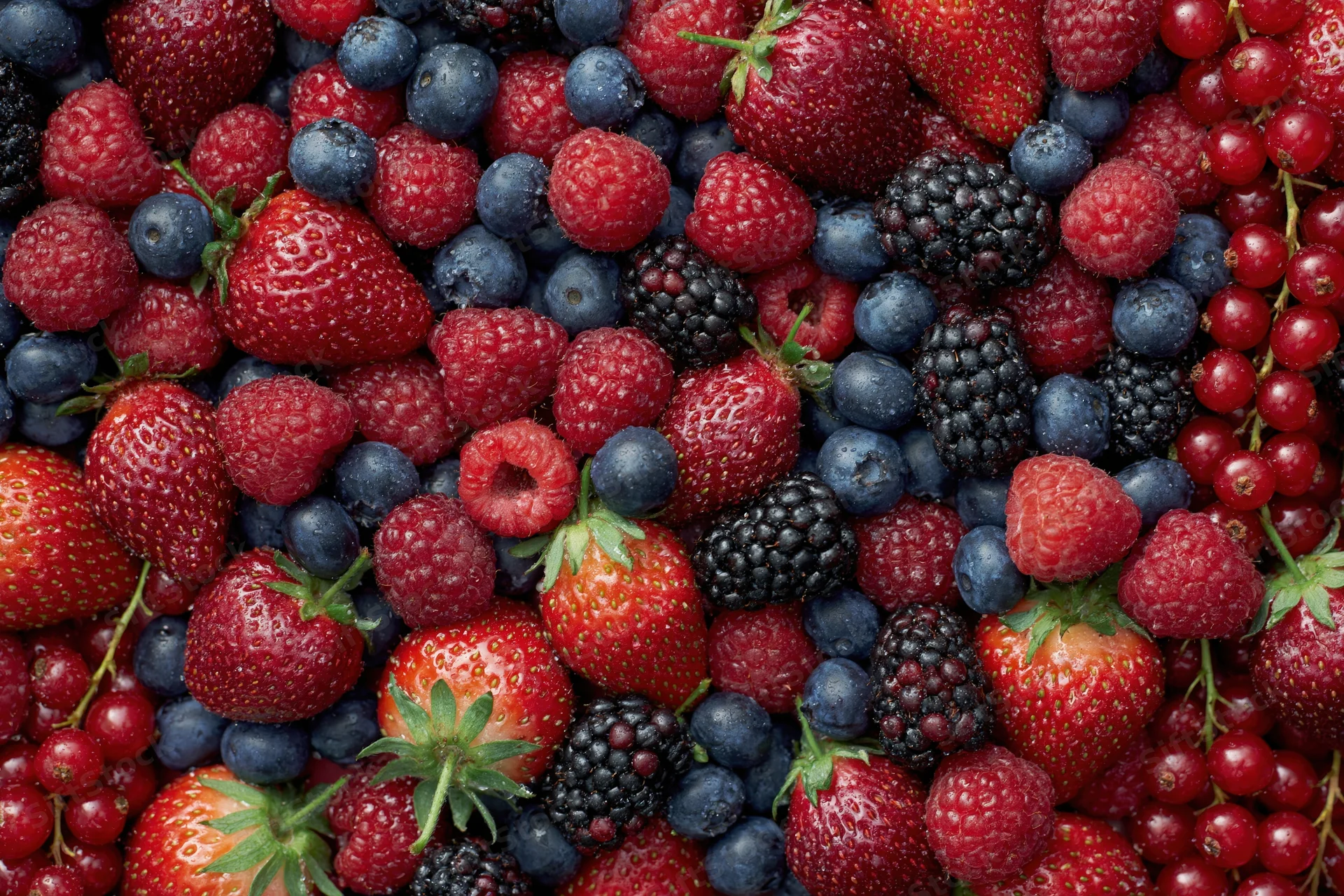 Overhead flat lay of mixed fresh berries densely covering the frame